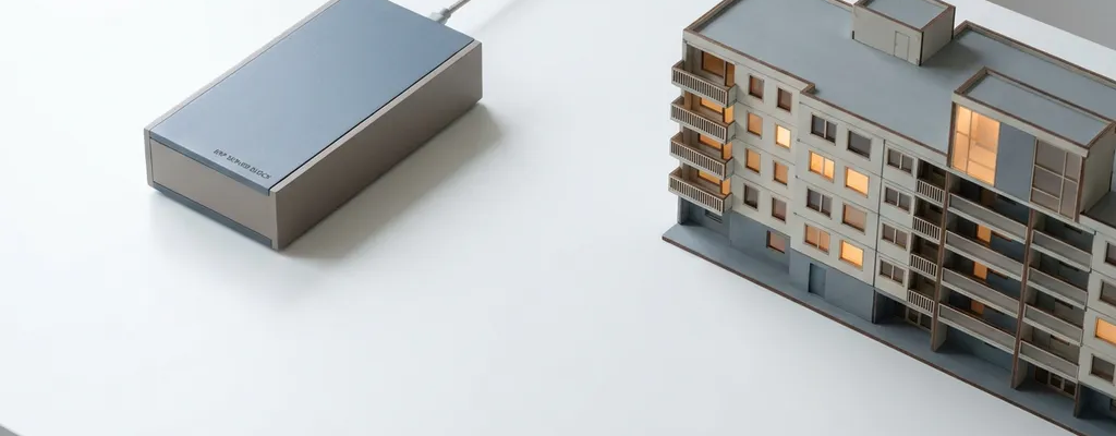ERP-server verbonden via kabel met een miniatuur appartementengebouw op wit bureau, architecturaal dwarsdoorsnede-diagram.
